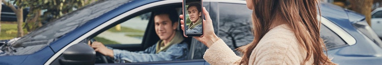 Actor portrayal of a mom taking a picture of her older teenage son driving in a car